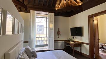 Un dormitorio con una cama grande, un escritorio, una silla, un televisor y una ventana con vistas al exterior.