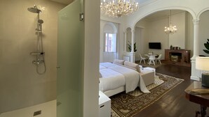 A hotel room with a shower, a bed, a chandelier, a fireplace, and a television. - Nava Suites (San Cristóbal de La Laguna)