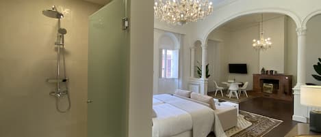 Una habitación de hotel con ducha, cama, candelabro, chimenea y televisión.