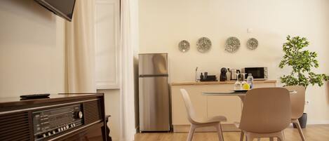 A modern kitchen with a refrigerator, microwave, and dining area with chairs and a table.
