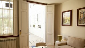 A room with a round table, a sofa, a radiator, and a door leading to a corridor. - Nava Suites (San Cristóbal de La Laguna)