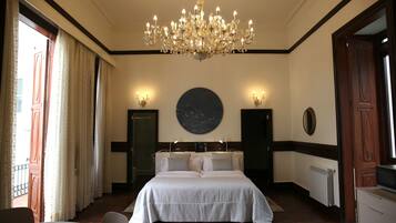 Een slaapkamer met een groot bed, een kroonluchter, een ronde wanddecoratie en twee bedlampjes.