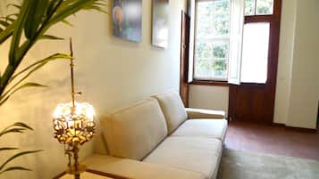 Un salon avec un canapé beige, un lampadaire décoratif et une fenêtre donnant sur un paysage verdoyant.