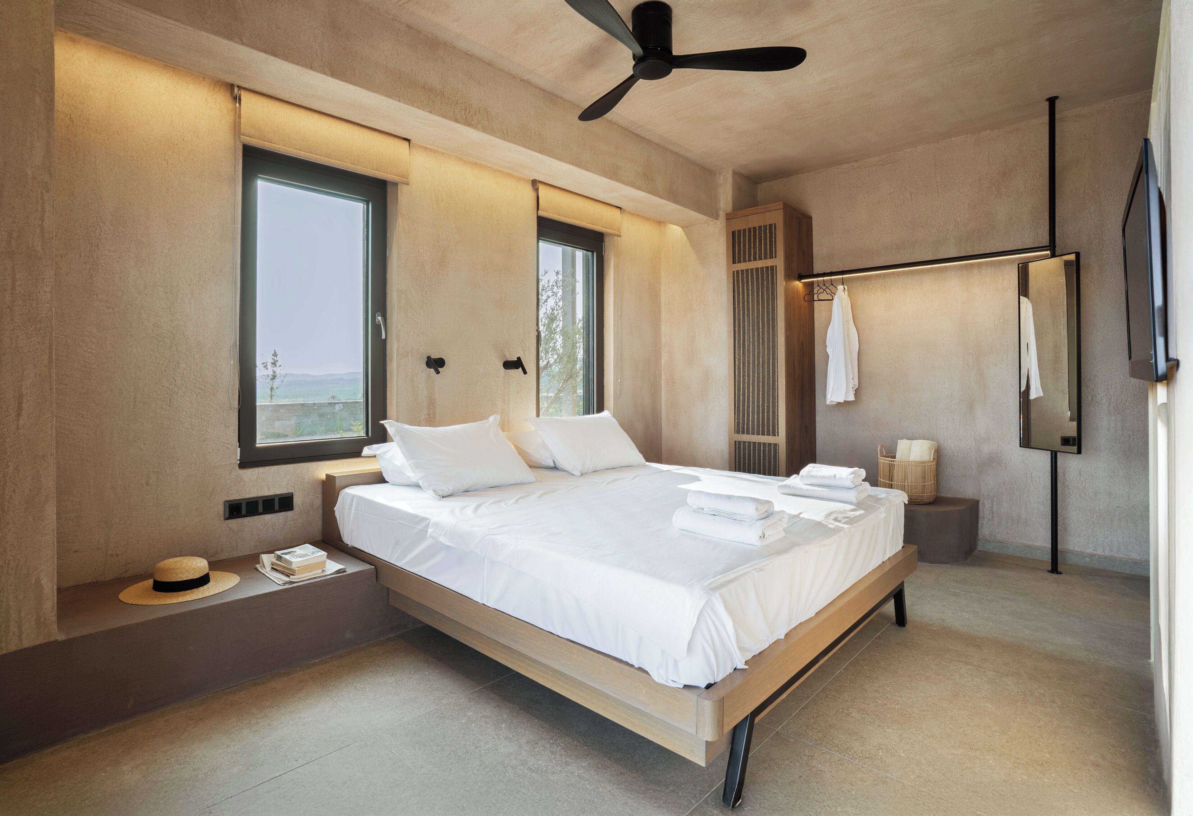 Une chambre moderne avec un grand lit, un ventilateur de plafond, une fenêtre et un miroir.