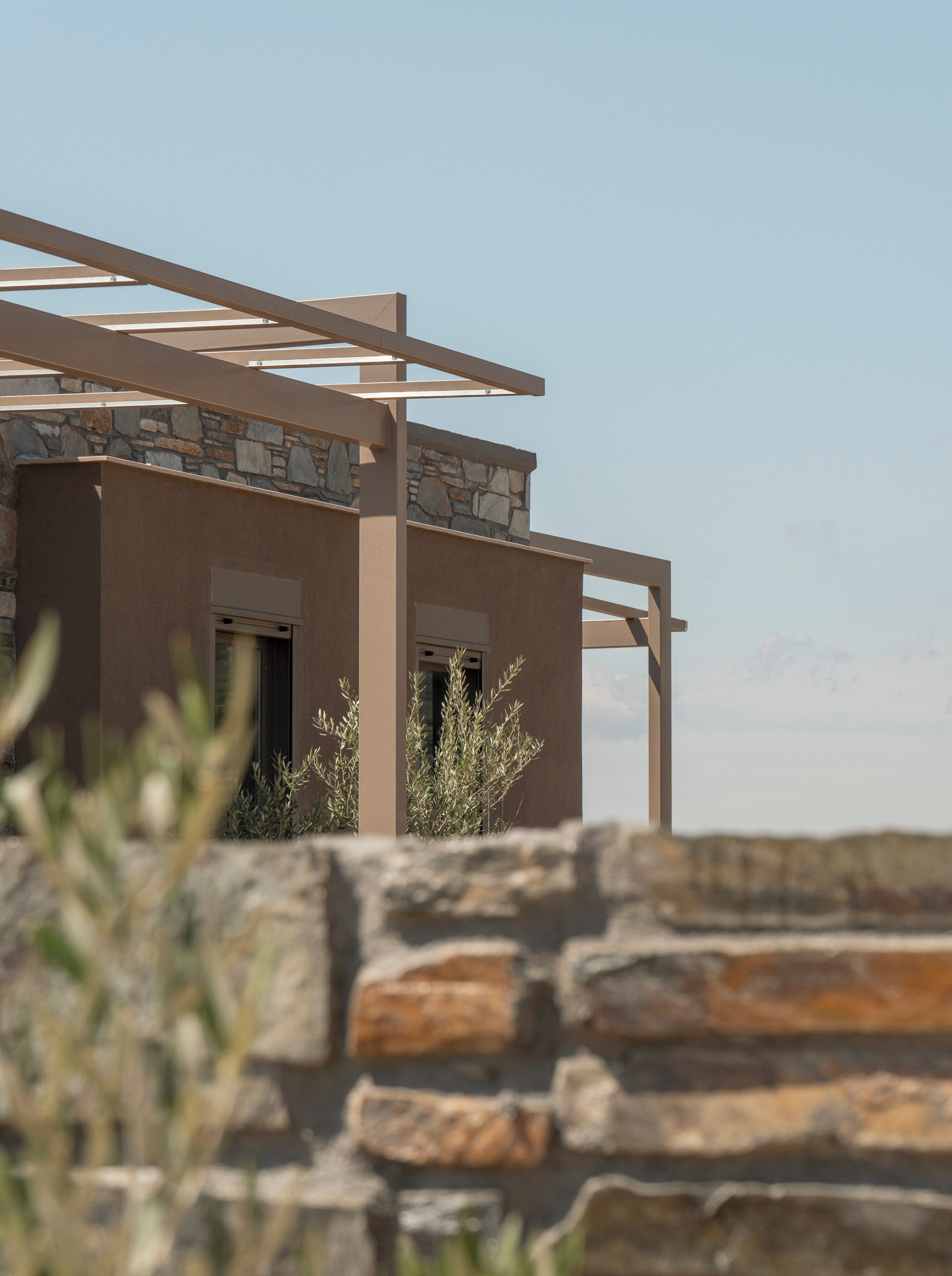 Un edificio moderno con fachada de piedra y una estructura de pérgola de madera.