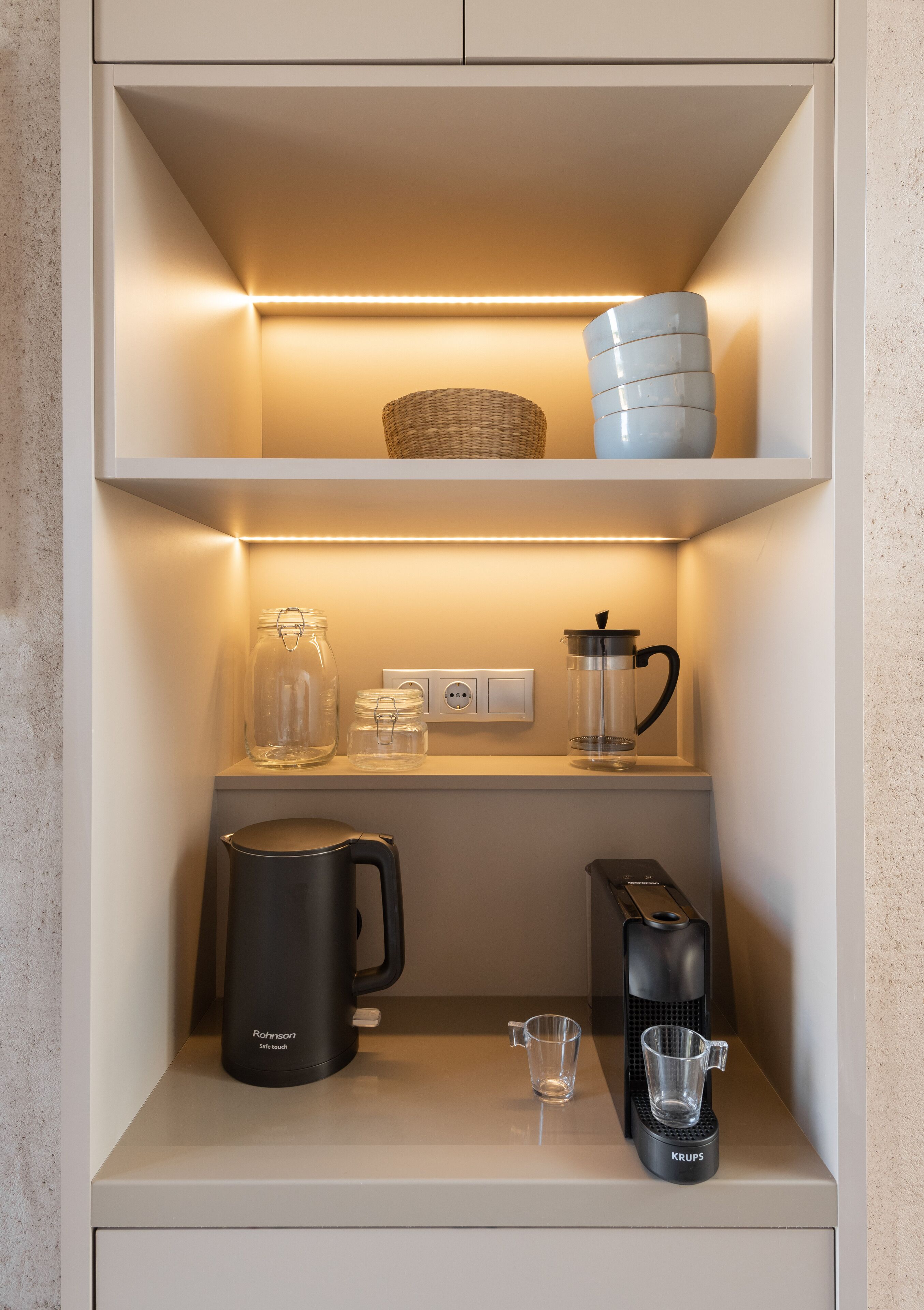 Eine Küche mit Kaffeemaschine, Wasserkocher und Glaskanne auf der Arbeitsfläche.