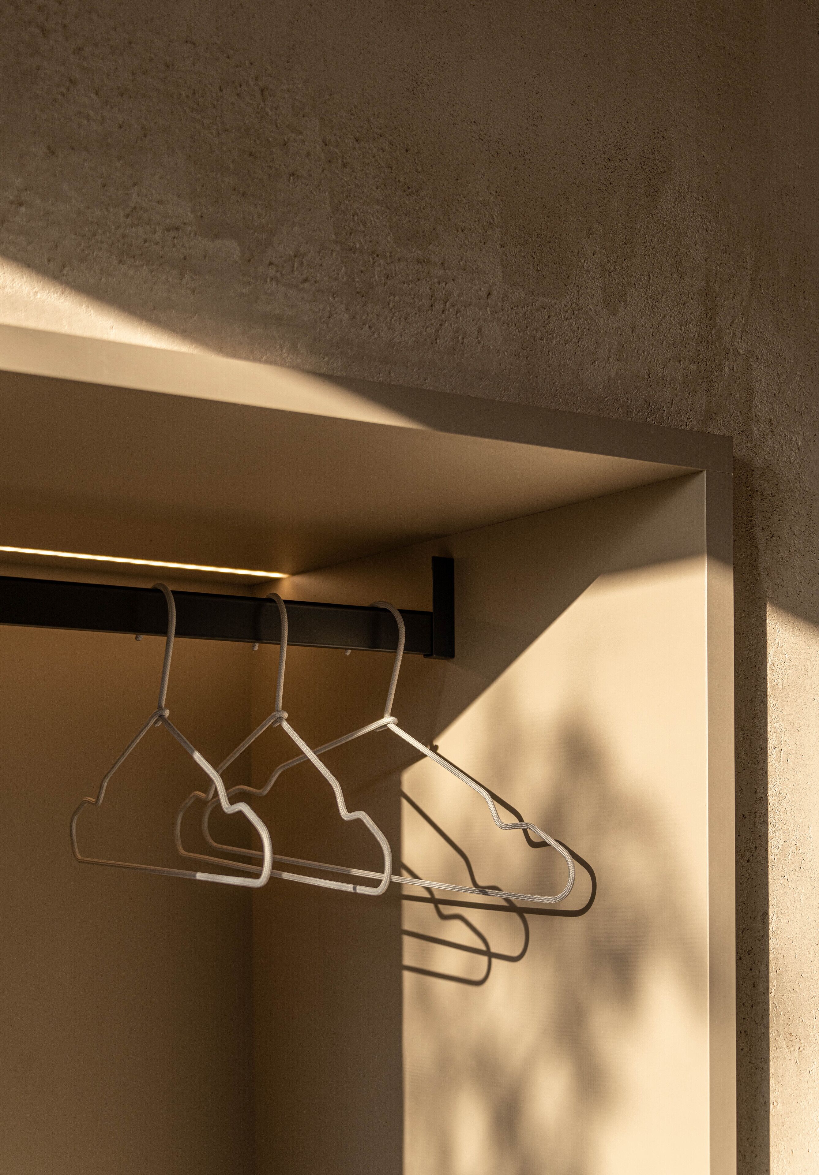 A hallway with a coat rack and a wall with a textured surface.