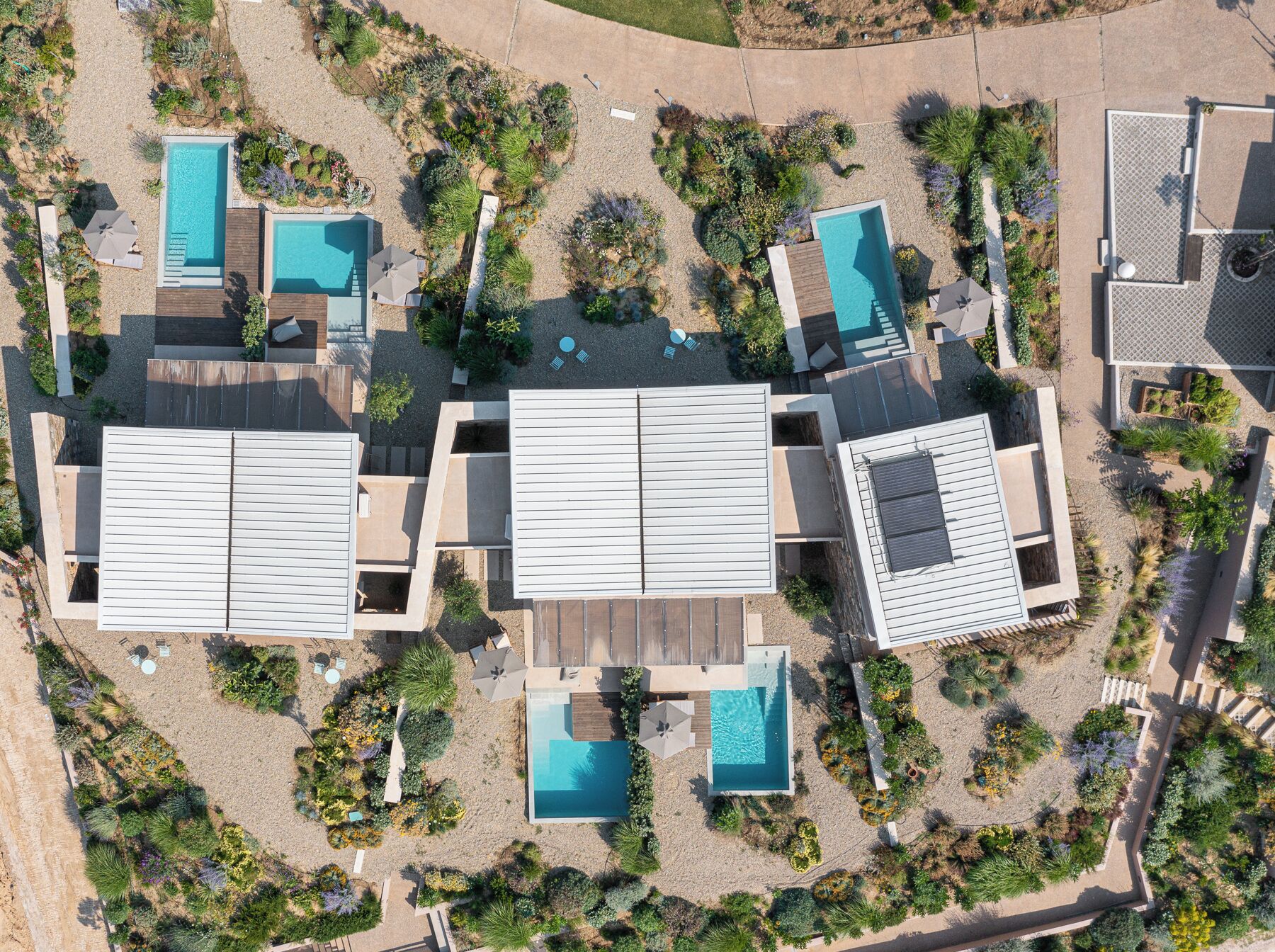 Vista aérea de un complejo turístico con múltiples piscinas, zonas de estar al aire libre y jardines ajardinados.
