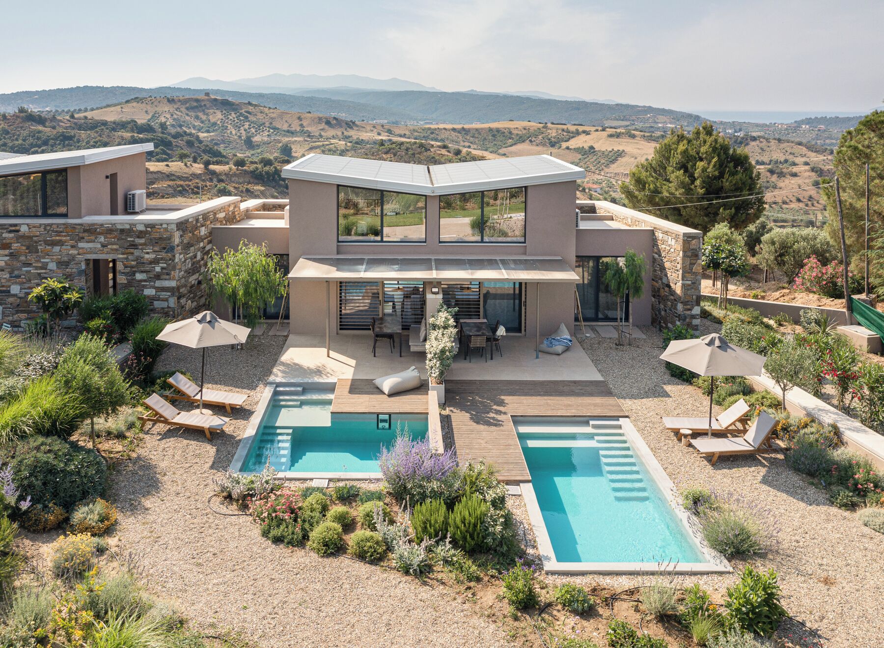 Ein modernes Haus mit Pool, Sitzgelegenheit im Freien und Blick auf die Hügel.