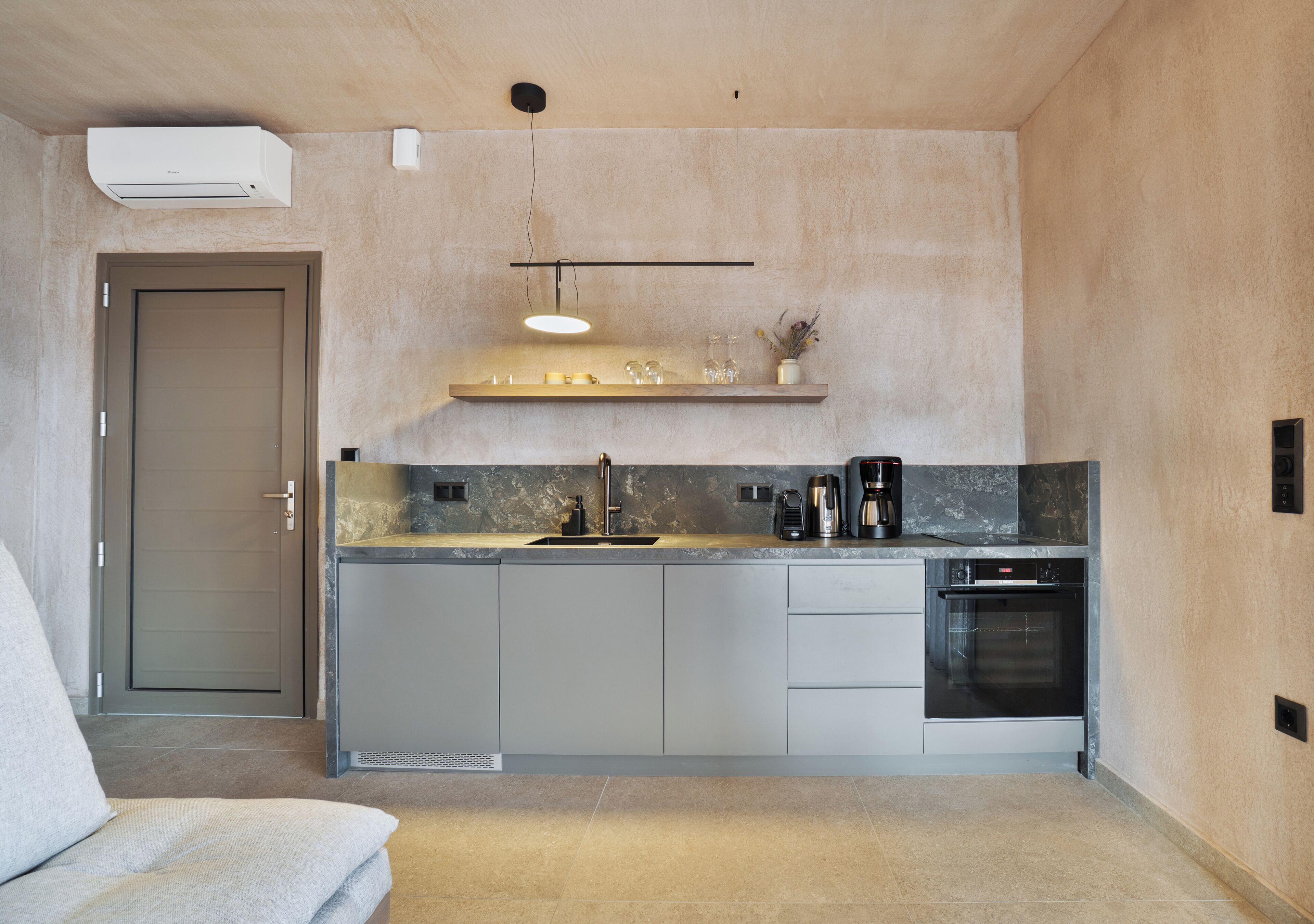 Een moderne keuken met een inbouwoven, een koffiezetapparaat en een hanglamp.