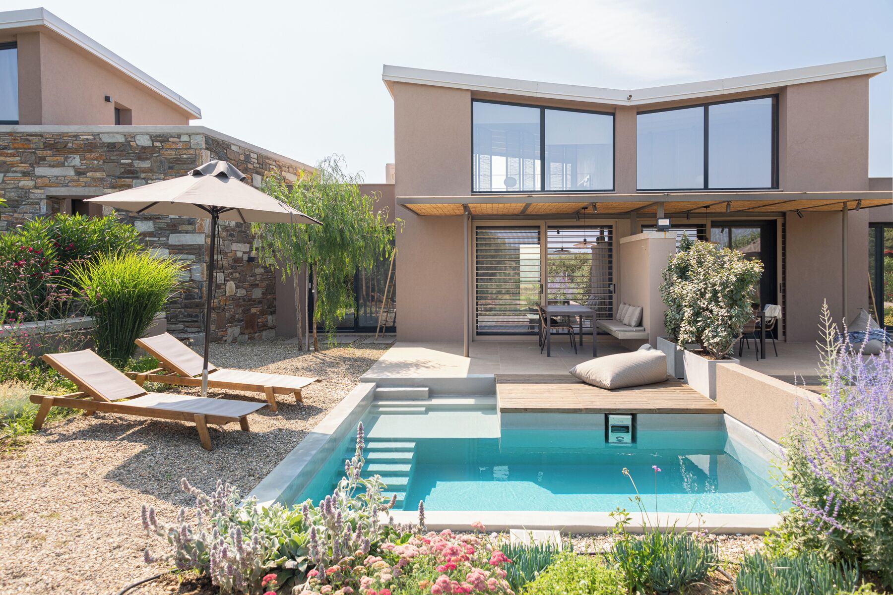 A modern house with a swimming pool, outdoor seating, and a patio area.