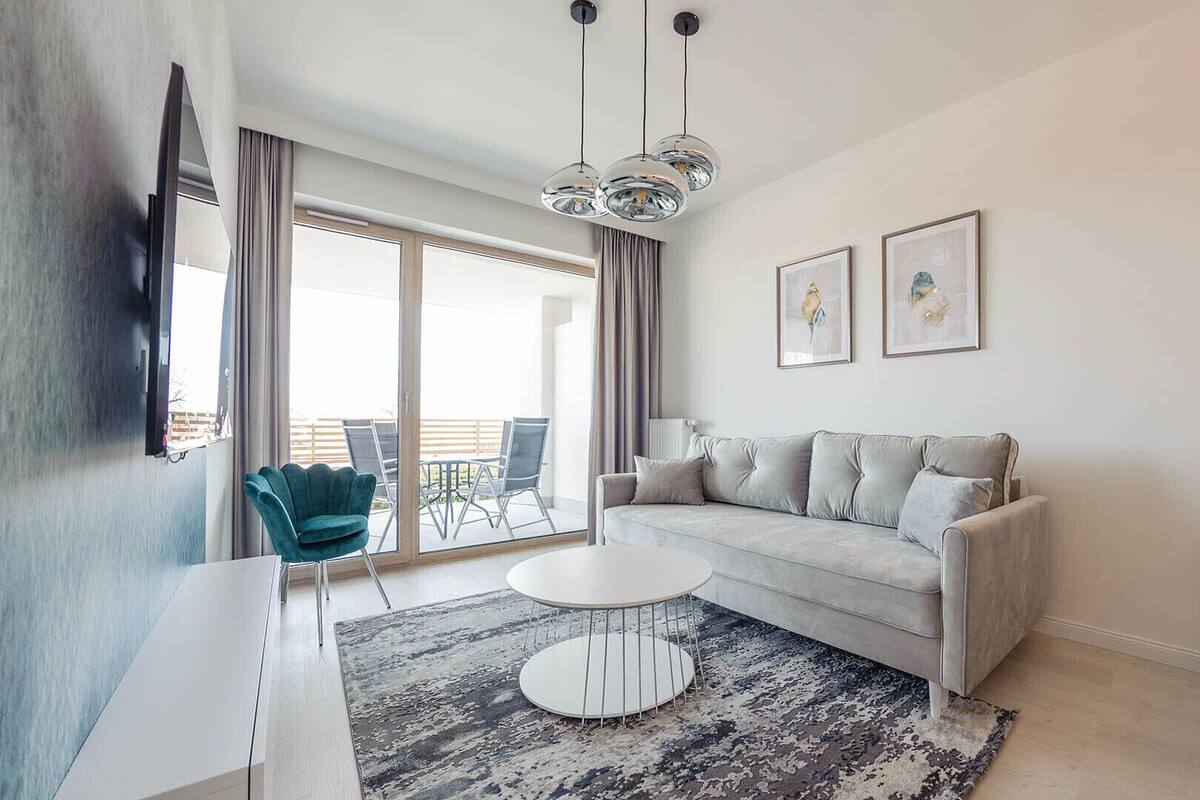 A modern living room with a grey sofa, a round coffee table, and a patterned rug.