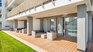 A modern outdoor lounge area with wicker furniture and a wooden deck. - Apartamenty Sun & Snow GEA ECO (Ustronie Morskie)