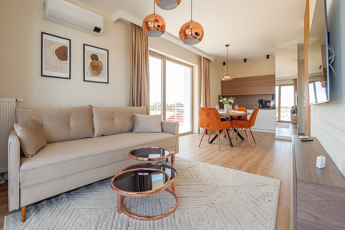 A modern living room with a sofa, coffee table, and dining area.