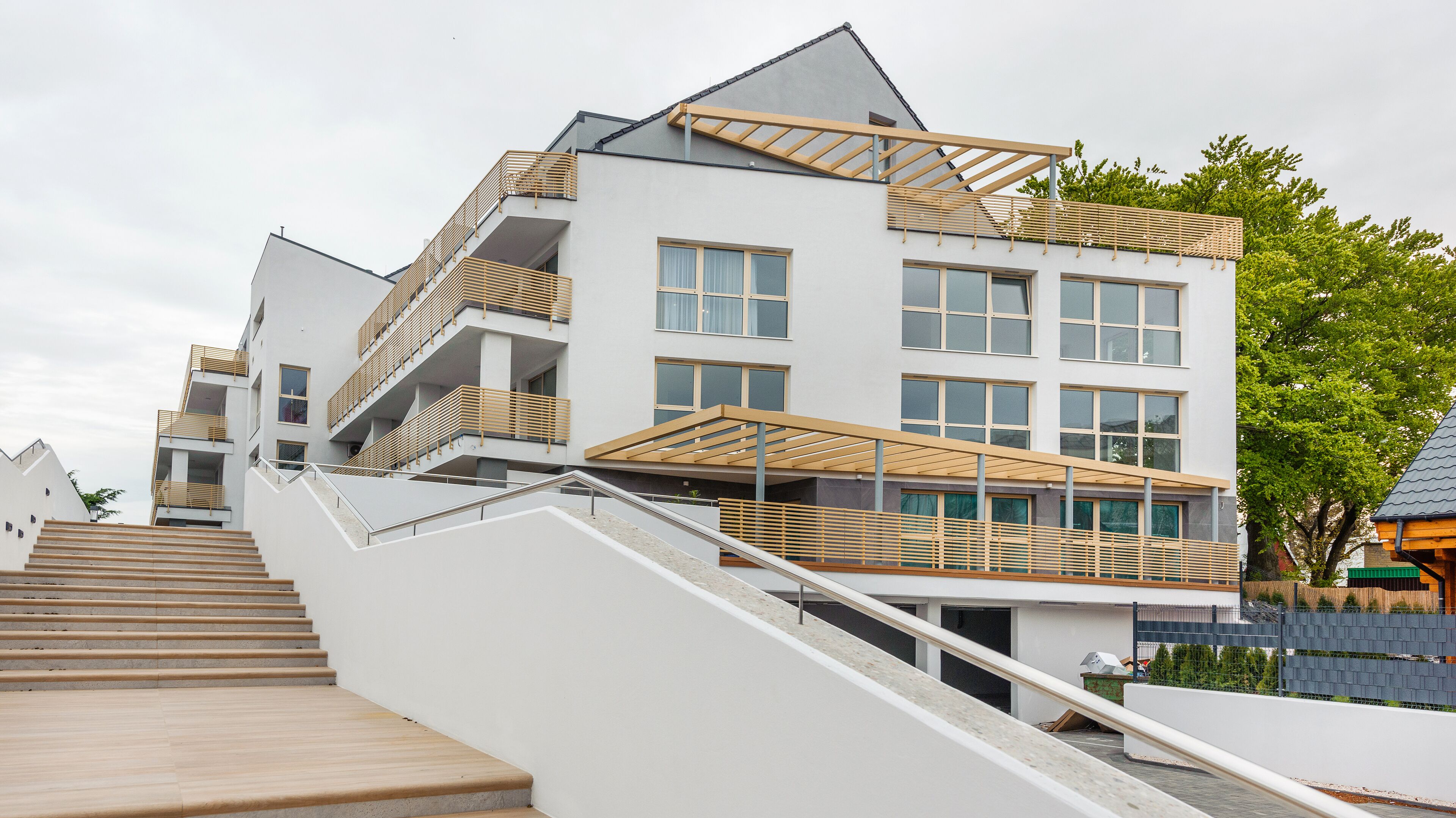 A modern multi-story building with a staircase leading to the upper floors, large windows, and a flat roof.