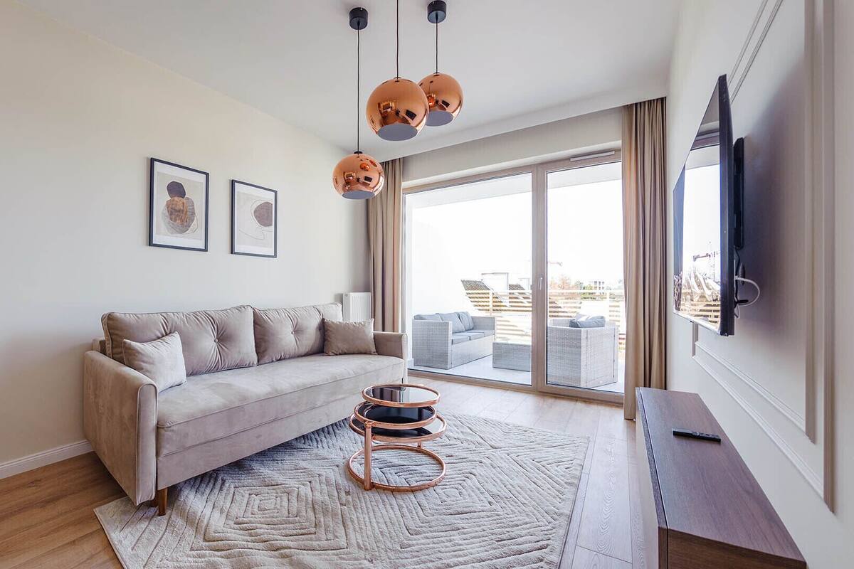 A modern living room with a sofa, a round coffee table, and a large window with a view.