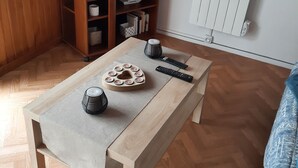 En stue med et træsofabord, et fjernsyn på et træstel og en radiator på væggen.