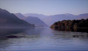 Un lago tranquilo con montañas al fondo.