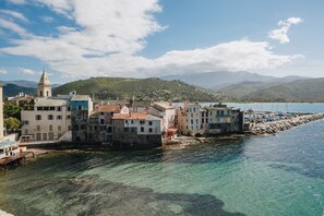 Une ville côtière avec des bâtiments qui bordent le front de mer, une eau cristalline et des montagnes en arrière-plan.