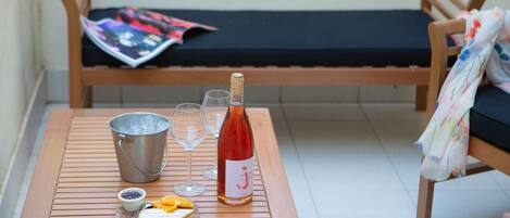 A wooden table with a bottle of wine, glasses, a bucket, and a cutting board with fruit.