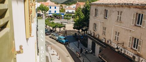 Vista de la calle con edificios, un restaurante llamado "Hotel Rurano" y un cartel que indica "San Rocco".
