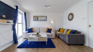 A modern living room with two sofas, a coffee table, a TV, and a framed artwork on the wall. - Homely 2-bed Apartment in London (London)