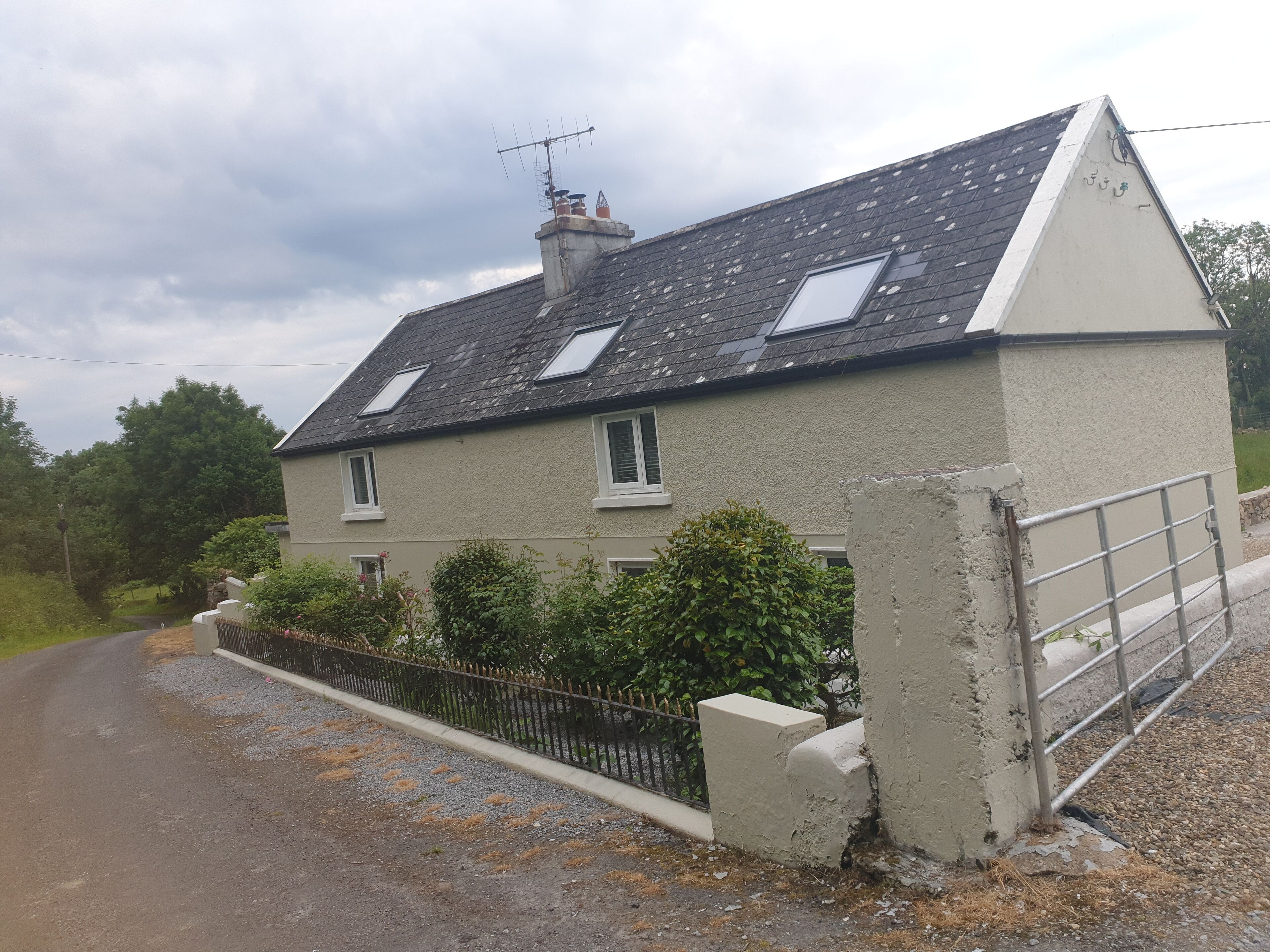 A two-story house with a sloped roof, a chimney, and a small garden area.