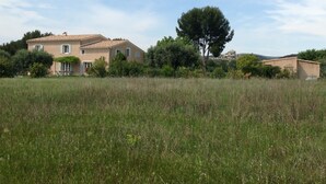 A two-story house with a tiled roof, surrounded by a grassy field and trees. - Magnificent villa with pool and view (Caromb)