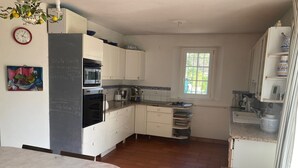 A kitchen with white cabinets, a black oven, a sink, and a window. - Magnificent villa with pool and view (Caromb)
