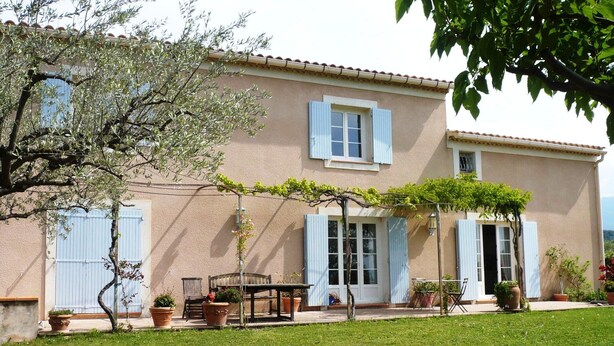 A two-story house with a garden, a table, chairs, and potted plants. - Magnificent villa with pool and view (Caromb)