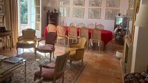 A dining room with a red tablecloth, multiple chairs, and framed artwork on the walls. - Magnificent villa with pool and view (Caromb)
