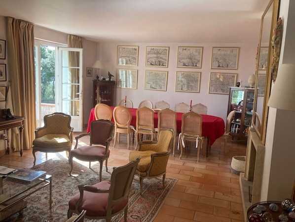 A dining room with a red tablecloth, multiple chairs, and framed artwork on the walls.
