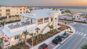Um hotel à beira-mar com um bar no terraço, estacionamento e vista para o oceano.