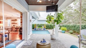 Um alpendre coberto com piscina, área de estar externa e vista para o quintal.