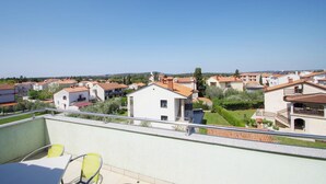 Ein Wohngebiet mit Häusern, einem Balkon mit gelben Stühlen und blauem Himmel.