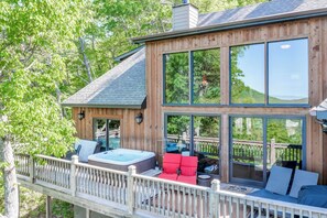 Une cabane en bois dotée d’une terrasse, d’un bain à remous et d’un espace détente avec des coussins.
