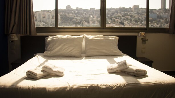 Habitación de hotel con una cama grande, dos almohadas y dos toallas dobladas.