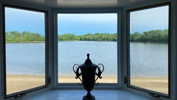 A room with a large window overlooking a lake and trees.