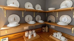 A kitchen with wooden shelves holding white dishes and cups, and a coffee station with labeled containers. - DUNDAS COTTAGE - 3 Bed in Richmond North Yorkshire (Richmond)