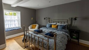 A bedroom with a bed, a window seat, a chair, and a bedside table. - DUNDAS COTTAGE - 3 Bed in Richmond North Yorkshire (Richmond)