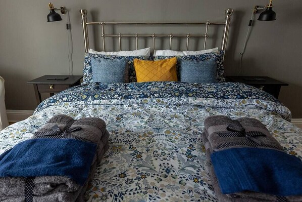 A neatly made bed with a floral bedspread, two pillows, and a headboard.