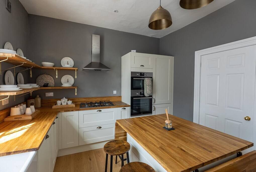 A modern kitchen with white cabinets, a wooden countertop, and a built-in oven.