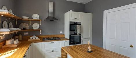 A modern kitchen with white cabinets, a wooden countertop, and a built-in oven.