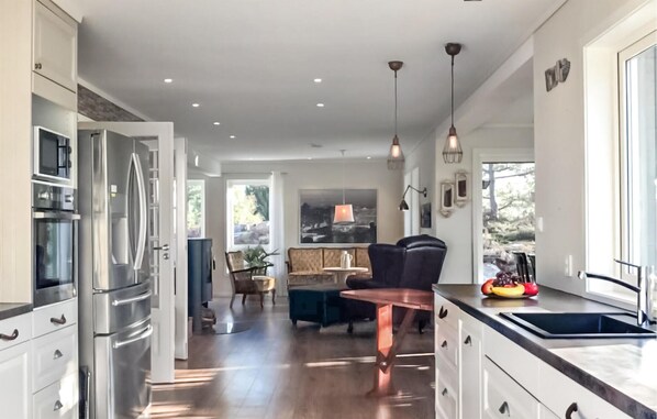 A modern kitchen with stainless steel appliances, a dining area with a table and chairs, and a view of the outdoors.