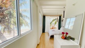 Een hotelkamer met een groot raam, een bed, een klein balkon en een houten vloer.