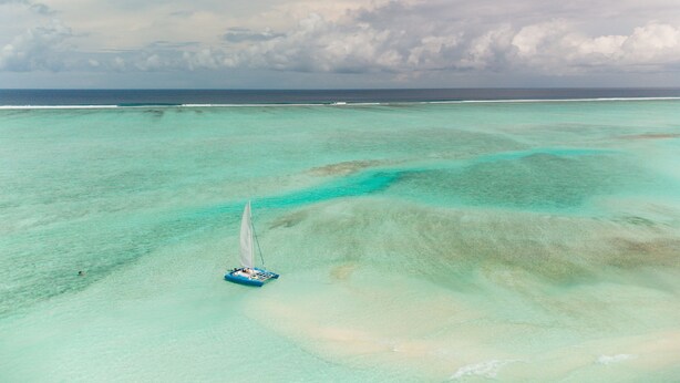 Luchtbeeld van een heldere turquoise zee met een klein bootje.