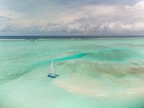An aerial view of a clear turquoise sea with a small boat.
