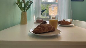 A breakfast table with croissants and a glass of orange juice, a potted plant, and a clock on the wall. - 2-bed Flat in Summerbridge Harrogate, Pet Friendly (Harrogate)