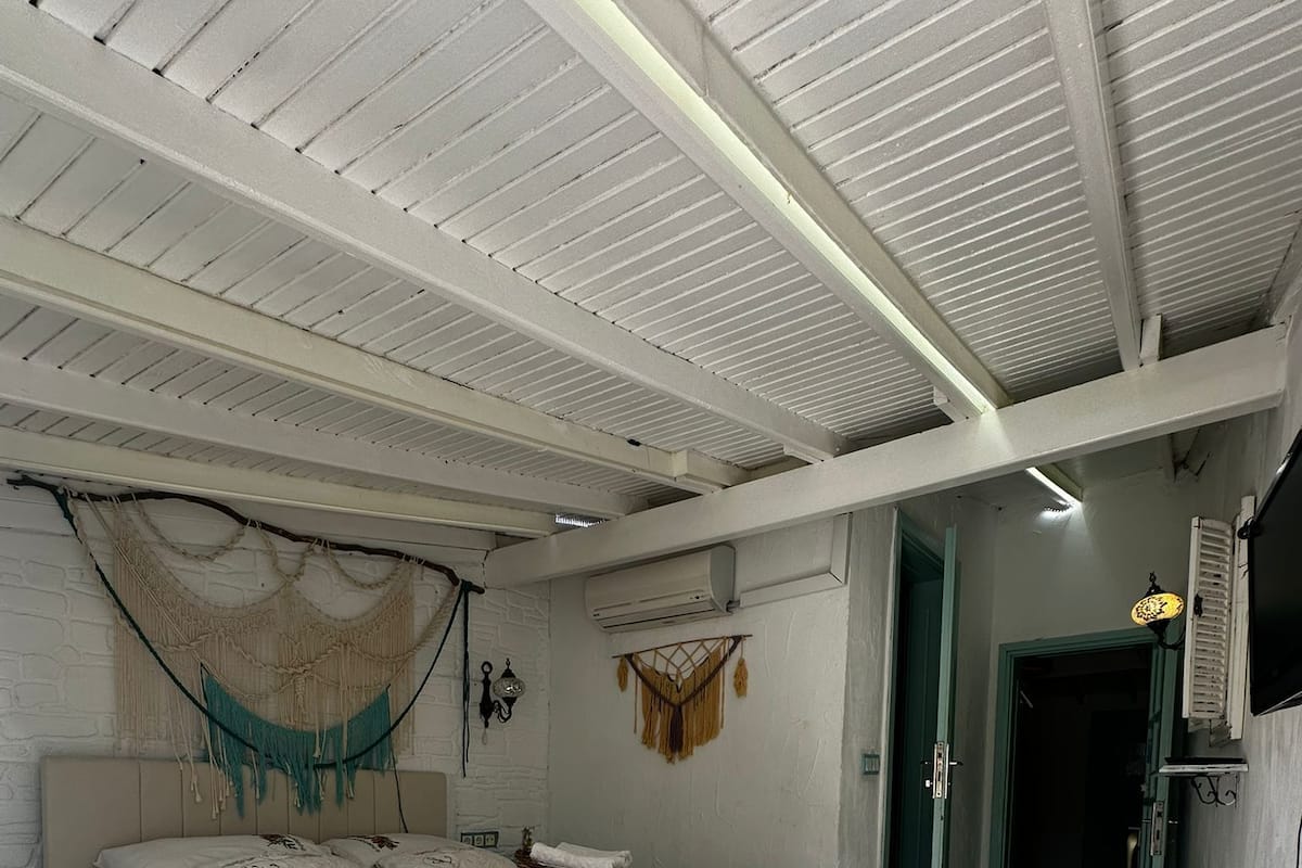 A bedroom with a bed, a wall-mounted air conditioner, a door, and a small rug.