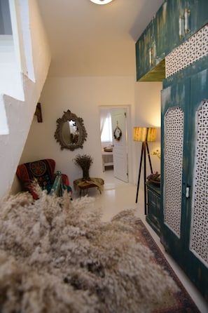 Cozy interior space with a traditional aesthetic, featuring a plush rug, armchair, and classic mirror.